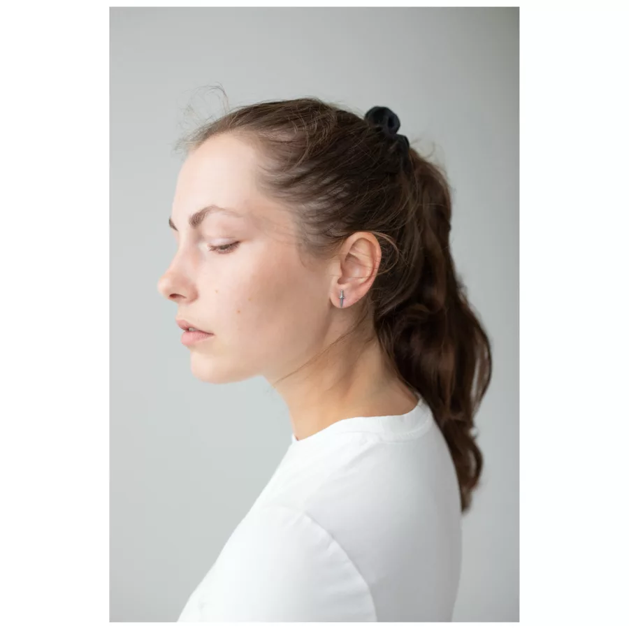 Donna con capelli lunghi indossa eleganti orecchini a spada in argento su sfondo grigio