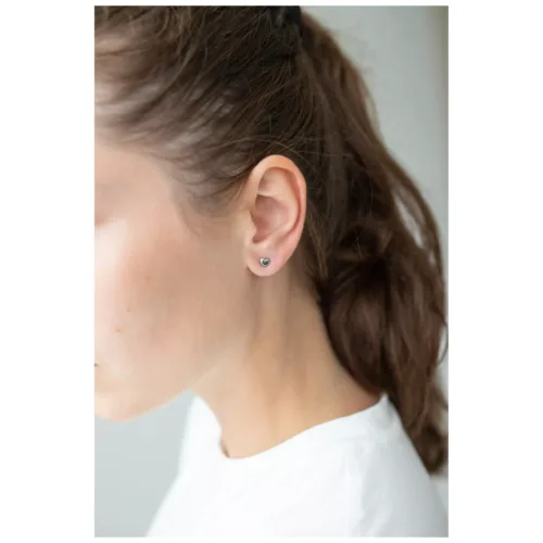 Orecchini a cuore argento su una donna con capelli castani, sfondo bianco