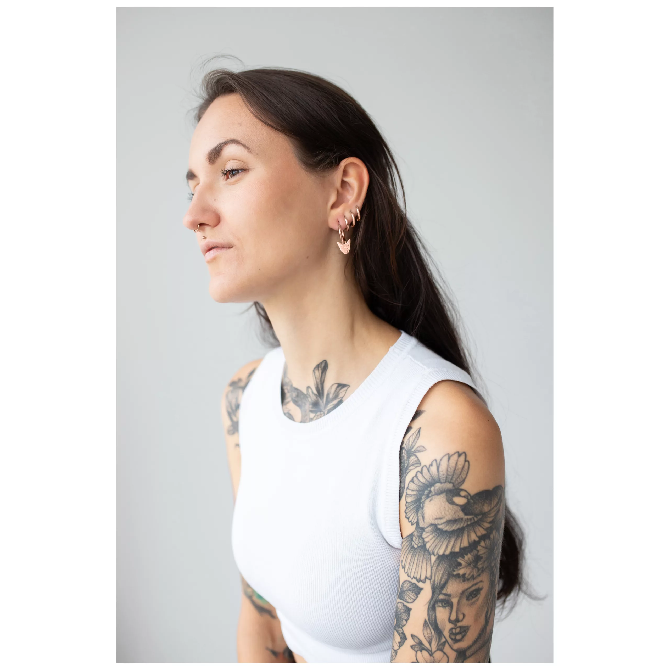 Donna con capelli lunghi indossa Little Sphynx Hoops in rosé su sfondo grigio