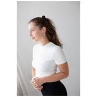 Donna con t-shirt bianca e eleganti orecchini in argento su sfondo neutro