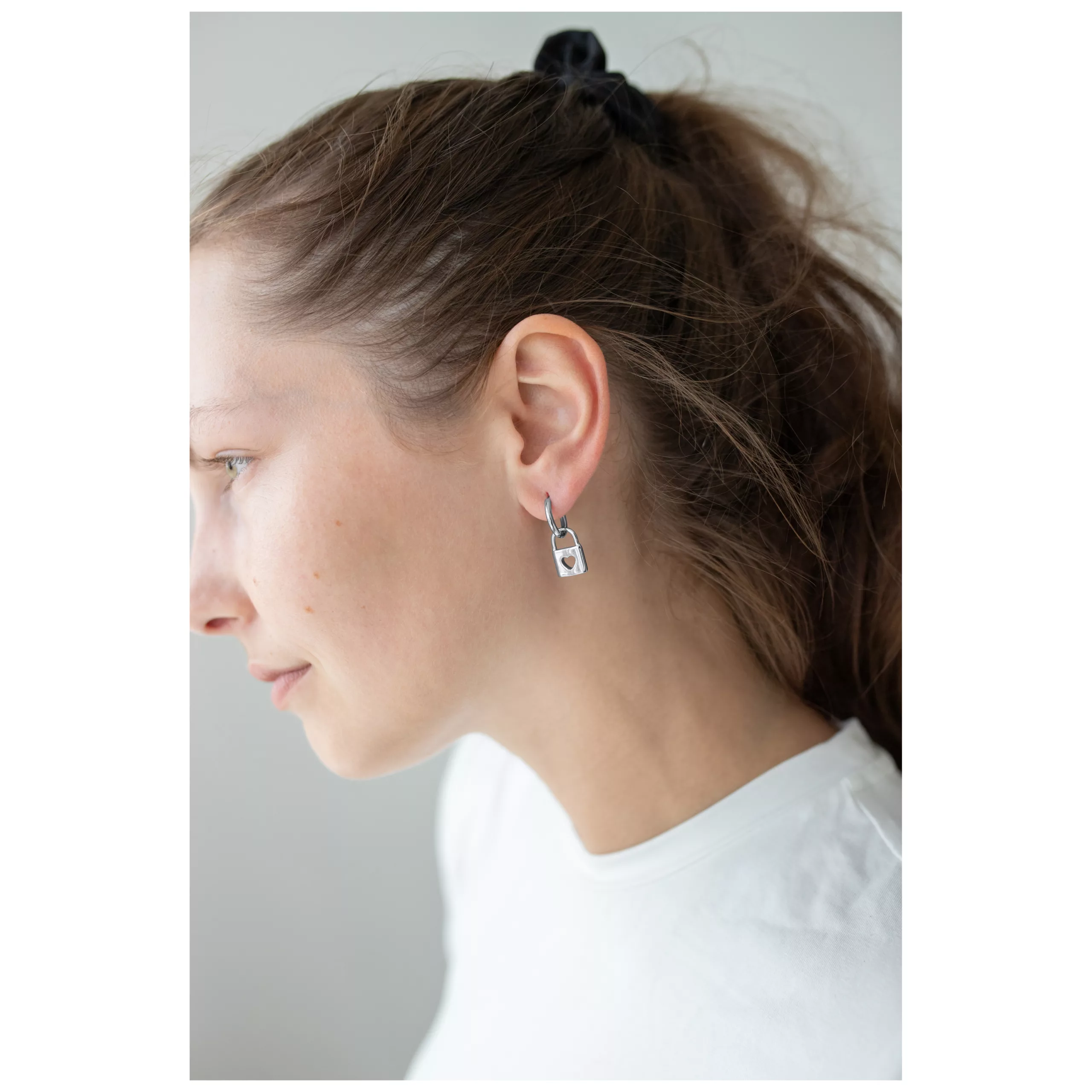 Donna indossa orecchini Little Lock Hoops in argento su sfondo bianco