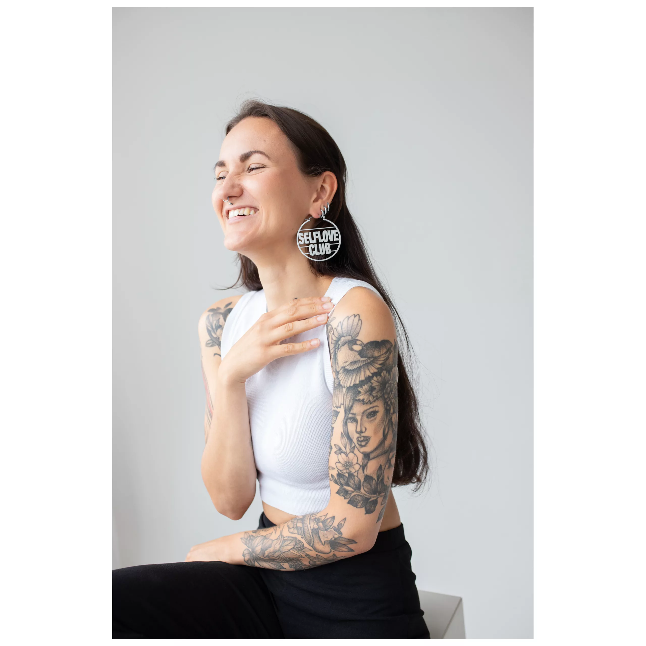 Persona sorridente con capelli lunghi e Selflove Club Hoops in una stanza luminosa