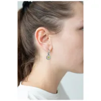 Orecchini d'argento a forma di margherita su un orecchio con capelli castani