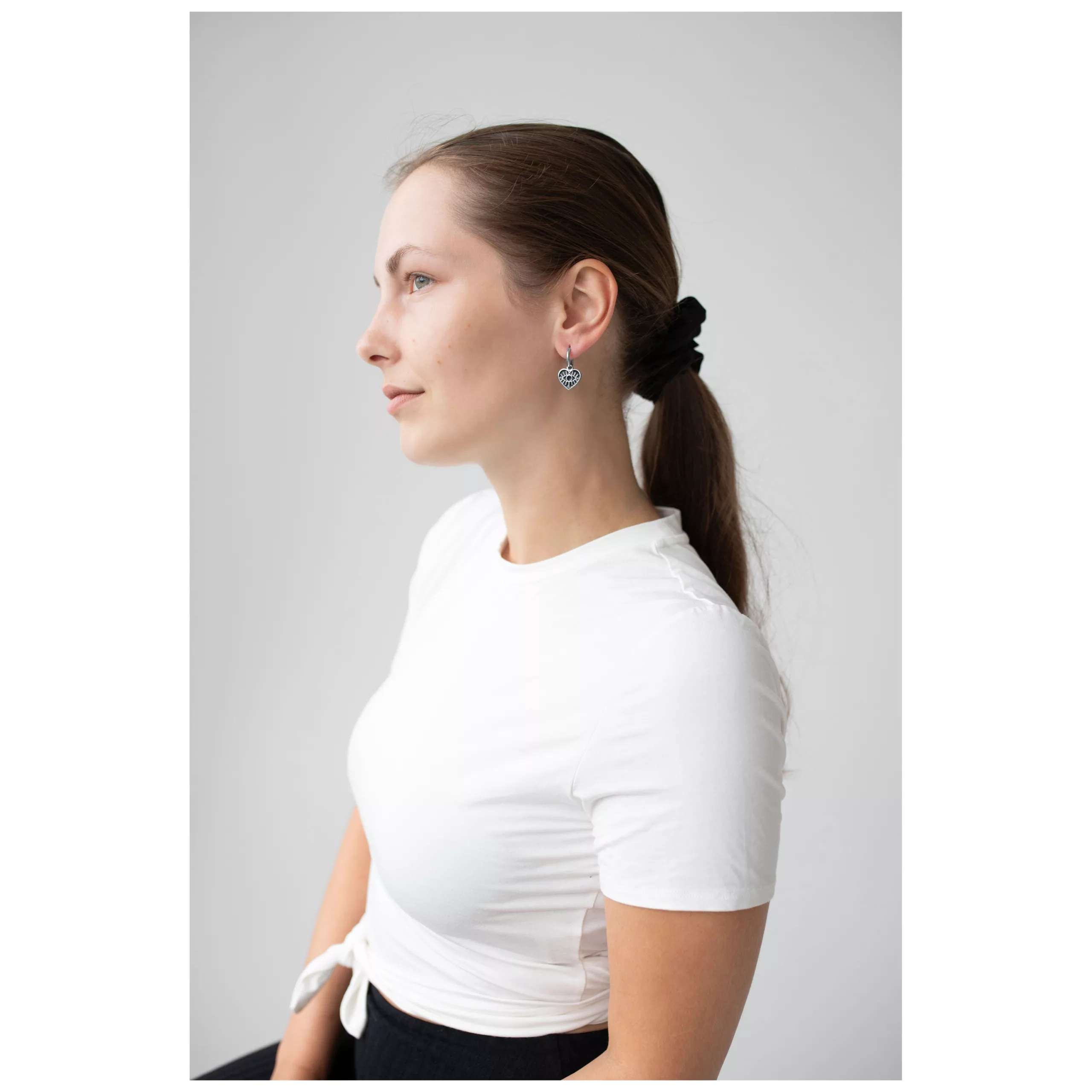 Donna con Little Soulmate Hoops in argento, maglietta bianca, profilo laterale