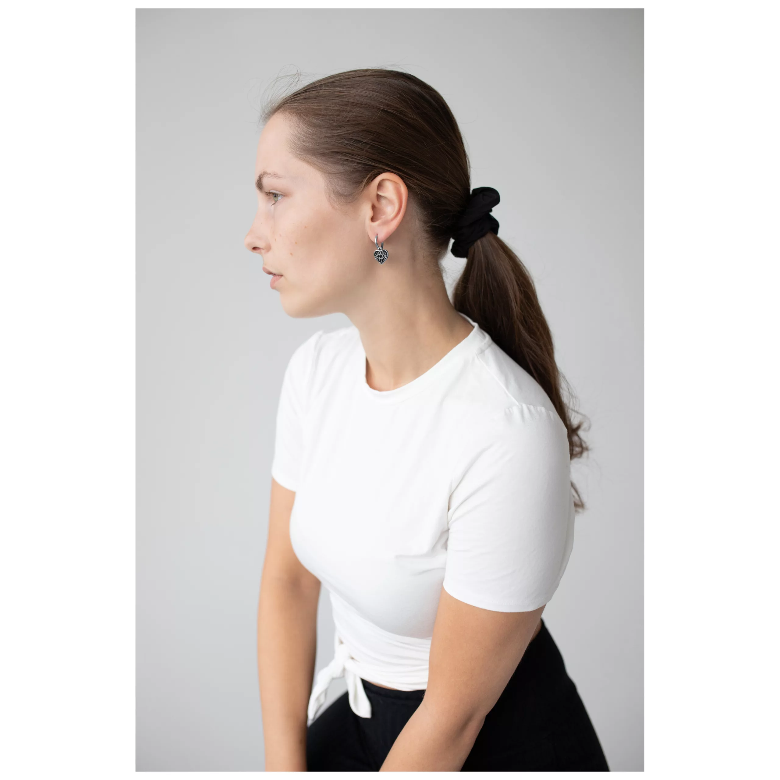 Donna con maglietta bianca indossa Little Soulmate Hoops in argento su sfondo grigio