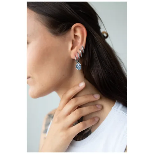 Orecchini a forma di serpente argento all'orecchio di una donna su sfondo chiaro