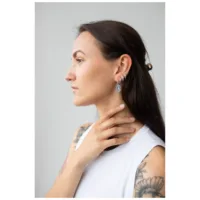 Donna con orecchini a cerchio Mystic Snake in argento, profilo laterale, top bianco