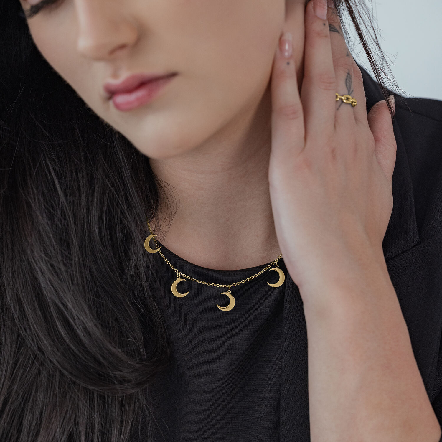 Collana Luna Dorata in Acciaio Chirurgico Collana dorata con piccoli ciondoli a forma di luna su sfondo nero indossata