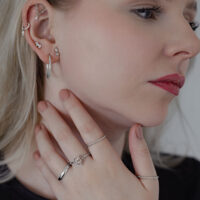 Donna con diversi orecchini che indossa un Twisted Ring in argento