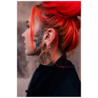 Persona con capelli rossi e orecchini a peso Twisted Rope dorati su sfondo neutro