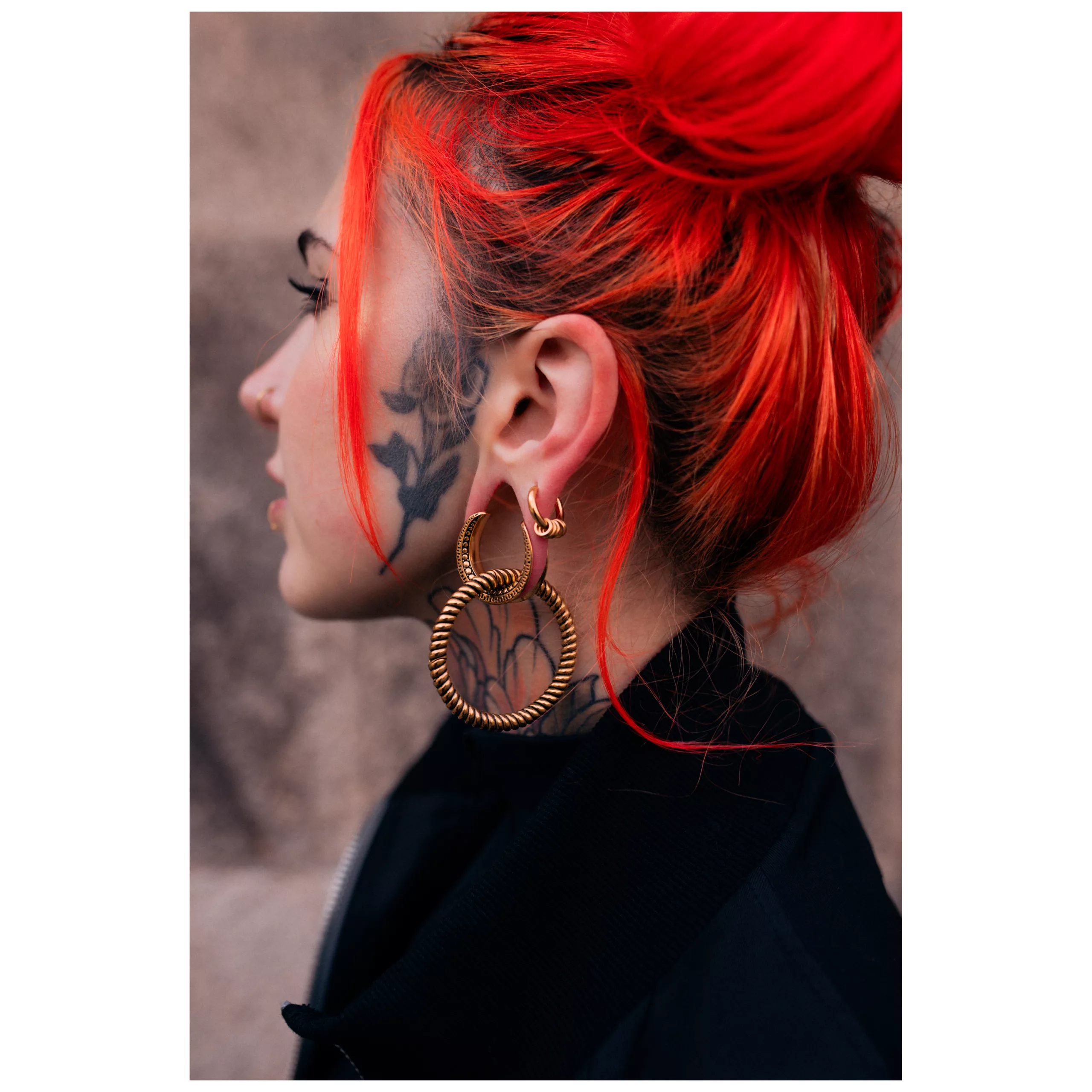 Persona con capelli rossi e orecchini a peso Twisted Rope dorati su sfondo neutro