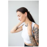 Donna con braccia tatuate indossa Oval Basic Hoops in argento su sfondo chiaro