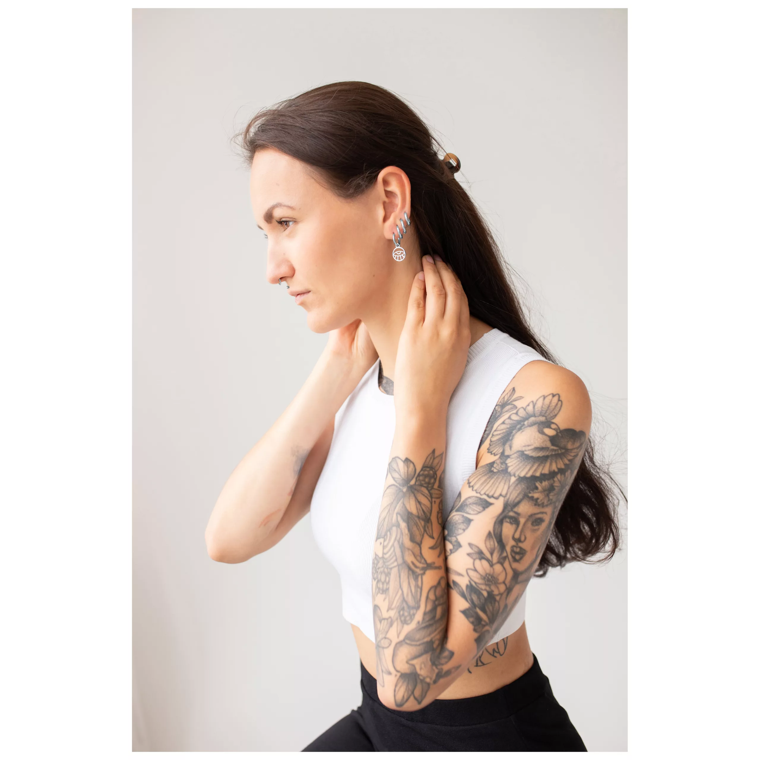 Donna con capelli lunghi e tatuaggi indossa orecchini Little Eye Hoops