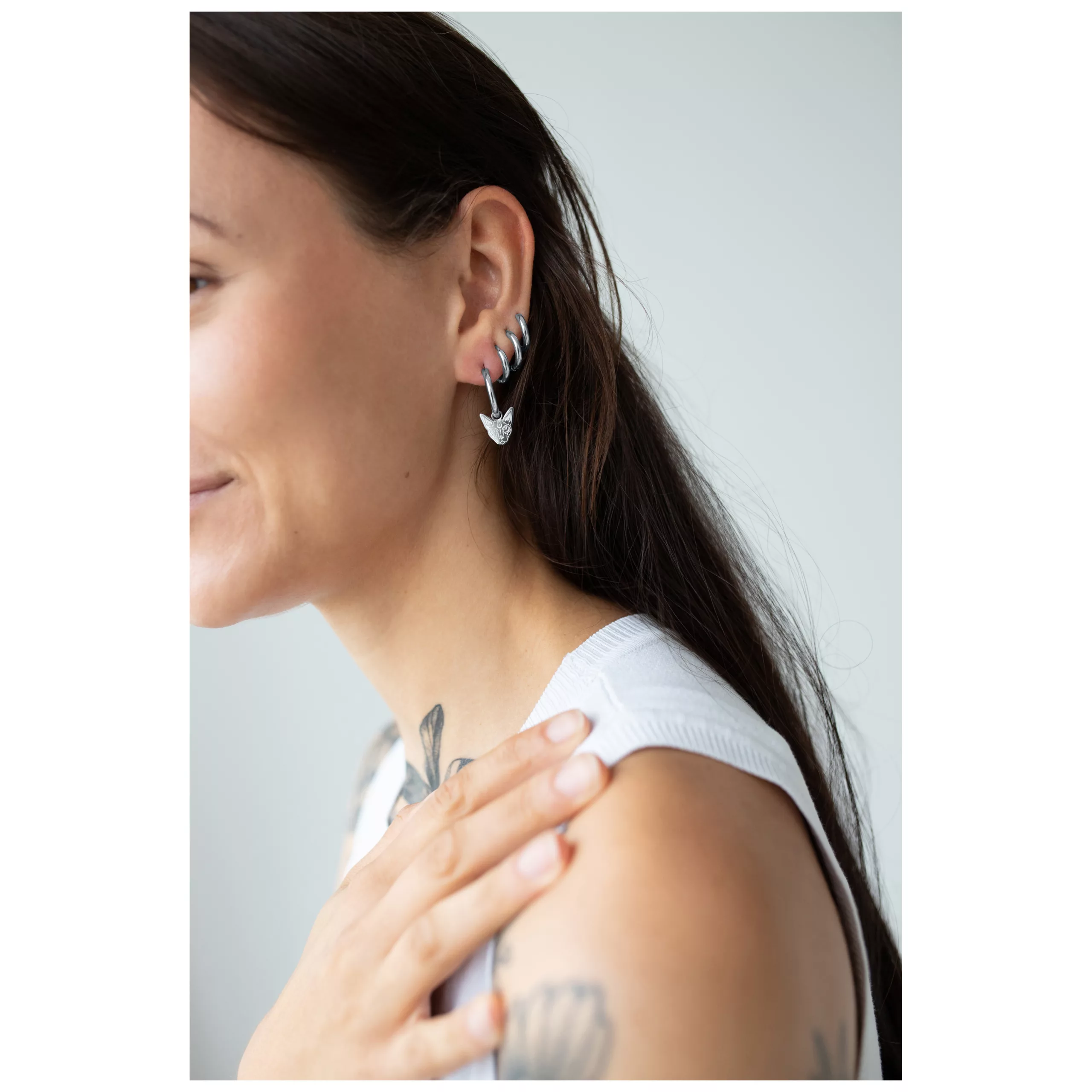 Donna con capelli lunghi indossa Little Sphynx Hoops in argento su sfondo chiaro
