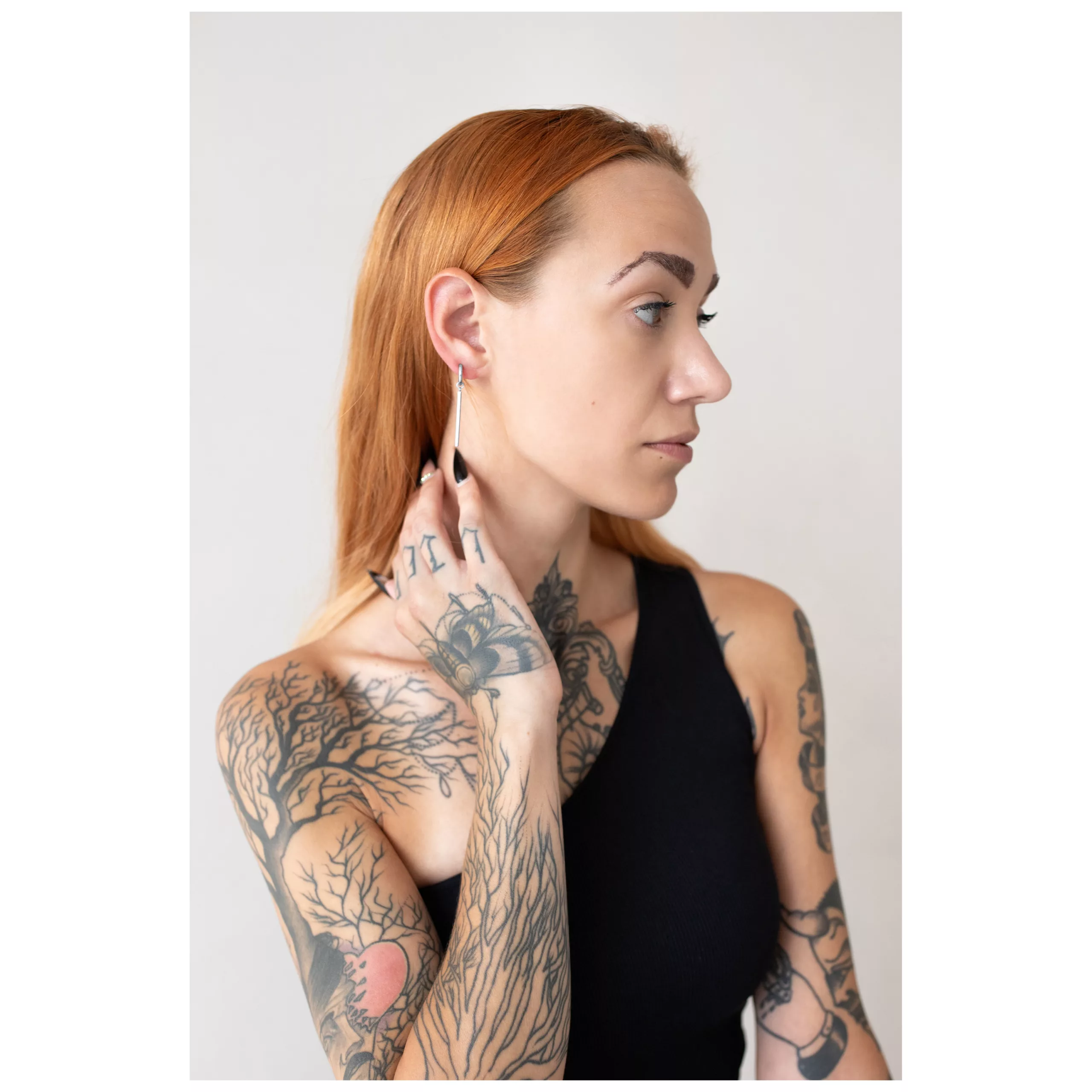 Donna con capelli rossi indossa orecchini Little Bar Hoops in argento su sfondo chiaro