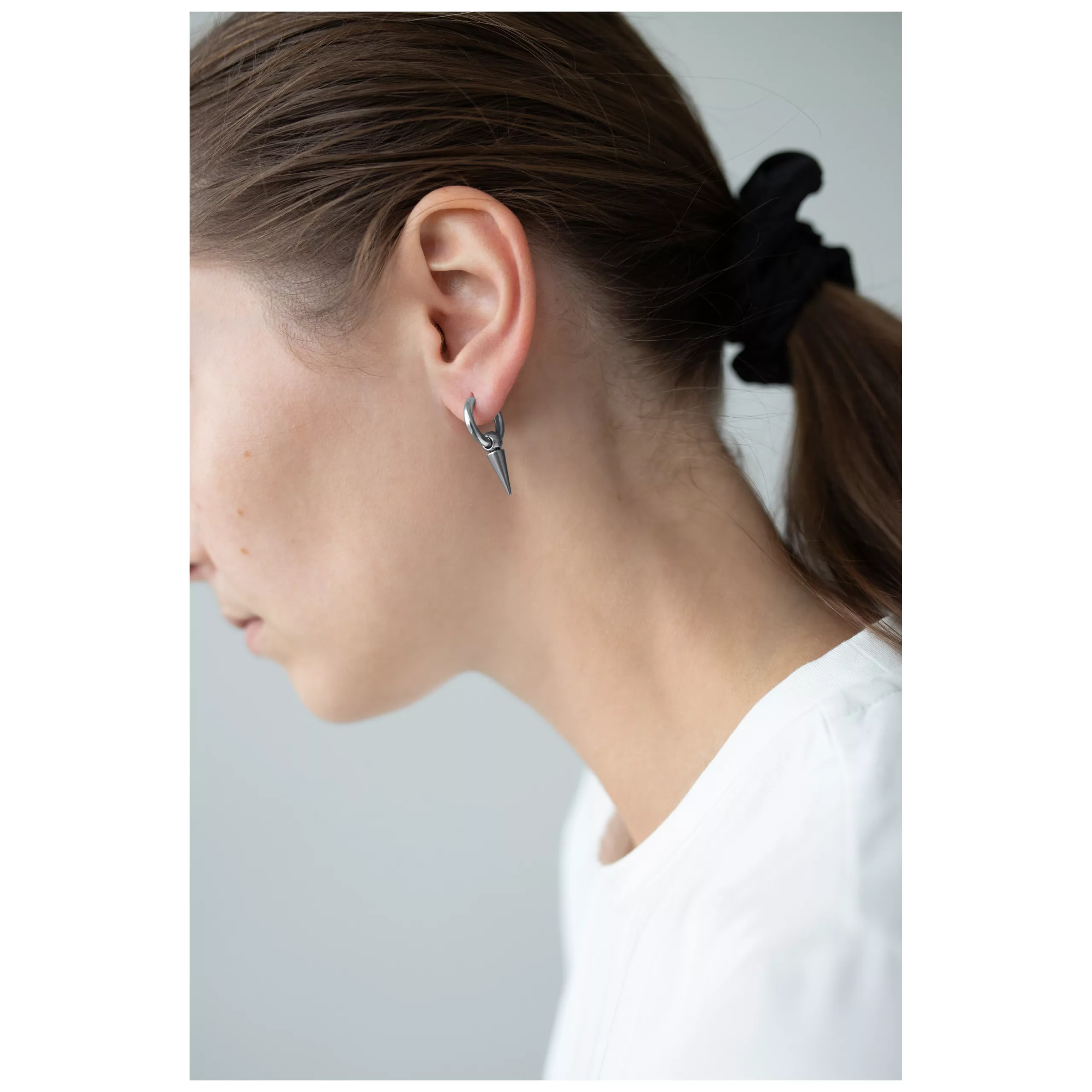 Donna con orecchini a spillo in argento, capelli raccolti, sfondo bianco