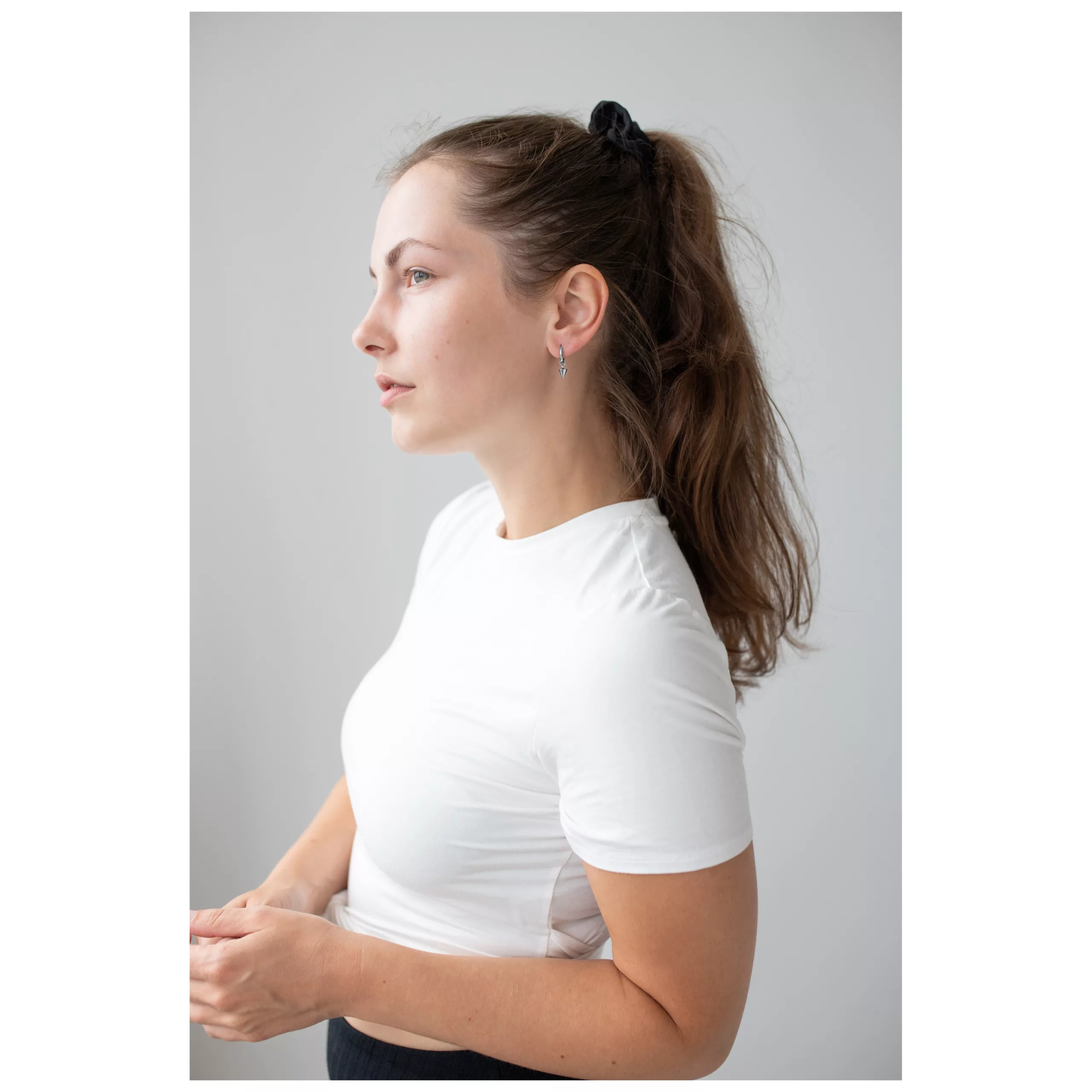 Donna con capelli lunghi indossa cerchietti a spillo neri su sfondo grigio