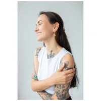 Donna con orecchini gold Little Moonchild Hoops e tatuaggi, sorridente