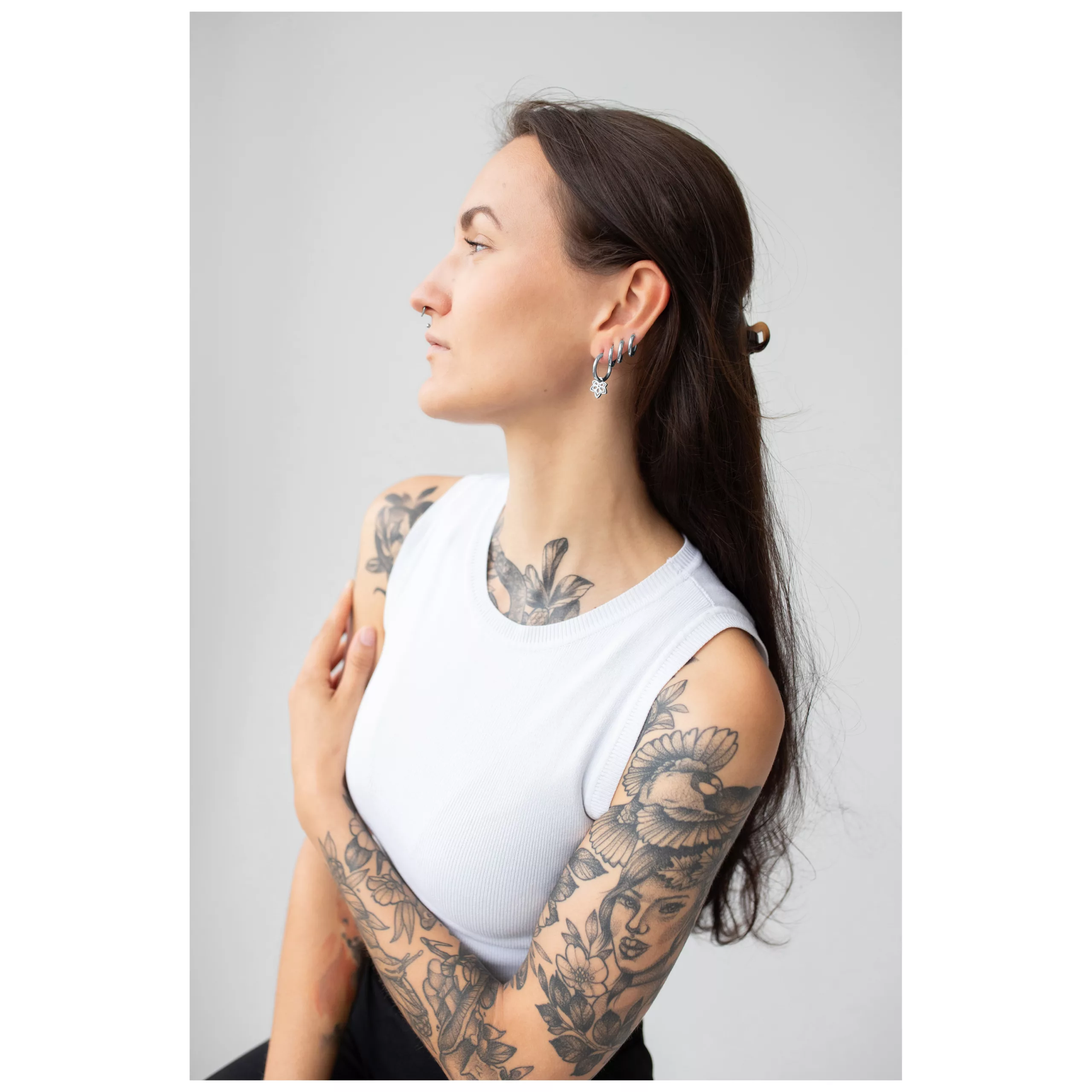 Donna con capelli lunghi indossa stilvolle Little Flower Hoops Orecchini su sfondo grigio