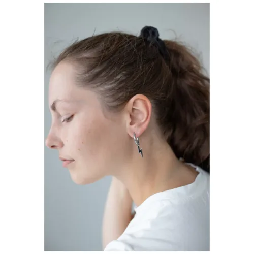 Donna con coda nera indossa orecchini Little Flash Hoops in acciaio chirurgico