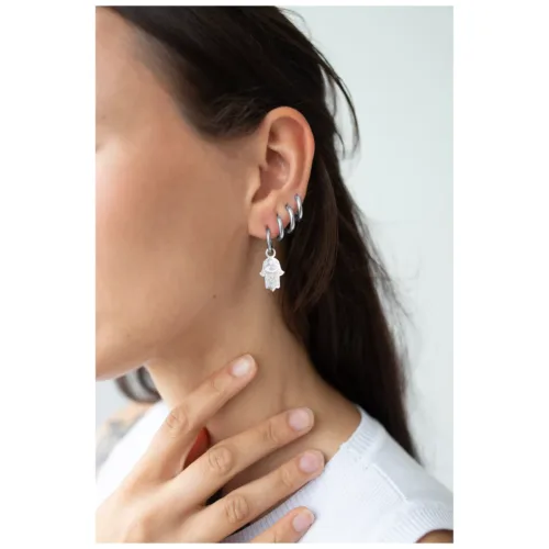 Primo piano di una donna con orecchini Little Hamsa Hand Hoops in argento che adornano l'orecchio