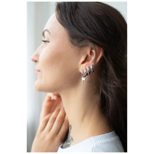 Donna indossa creoli neri e argento lucenti con ciondolo a palma