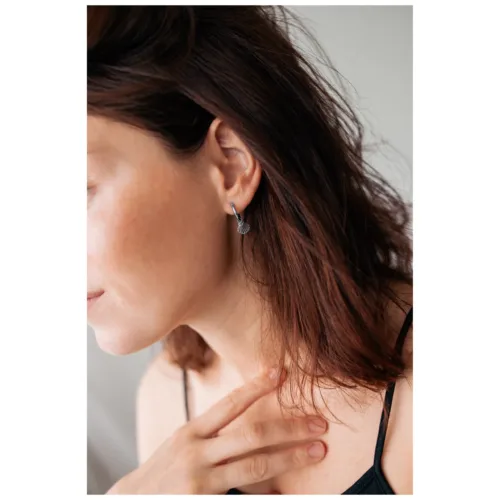 Orecchini in argento a forma di conchiglia su un orecchio con capelli castani e pelle chiara