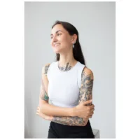 Giovane donna con braccia tatuate indossa Little Moon Coffin Hoops su sfondo chiaro