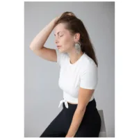 Donna con maglietta bianca indossa eleganti orecchini La Fleur in argento su sfondo grigio