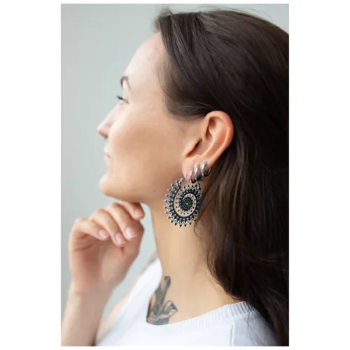 Donna con Floral Nautilus Hoops in argento e oro su sfondo neutro