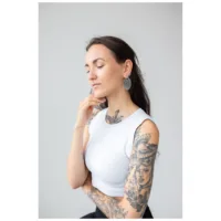 Donna con braccio tatuato indossa orecchini Floral Nautilus Hoops in argento su sfondo grigio