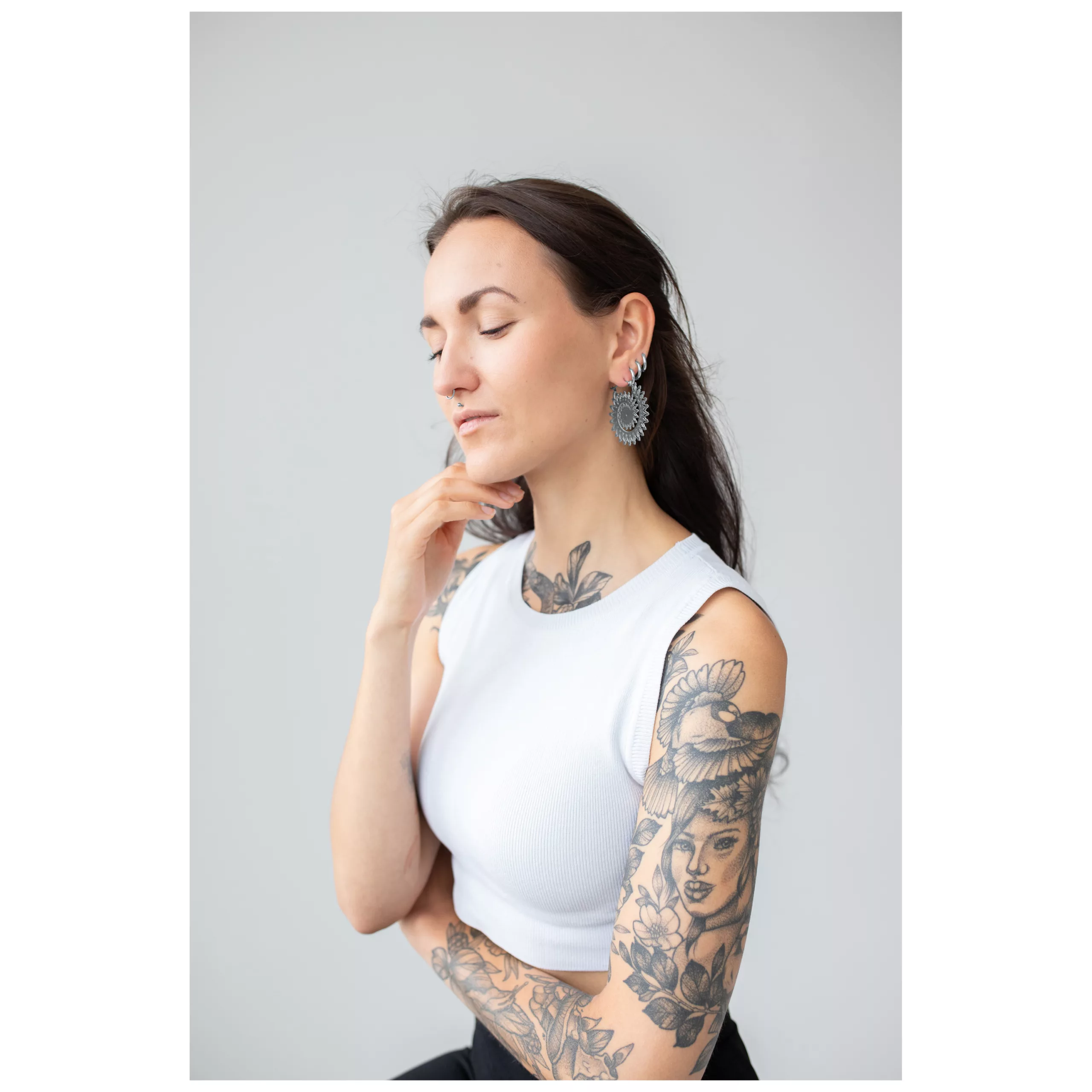 Donna con braccio tatuato indossa orecchini Floral Nautilus Hoops in argento su sfondo grigio