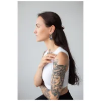Donna con orecchini Magnolia Hoops, acciaio inossidabile nero su sfondo grigio