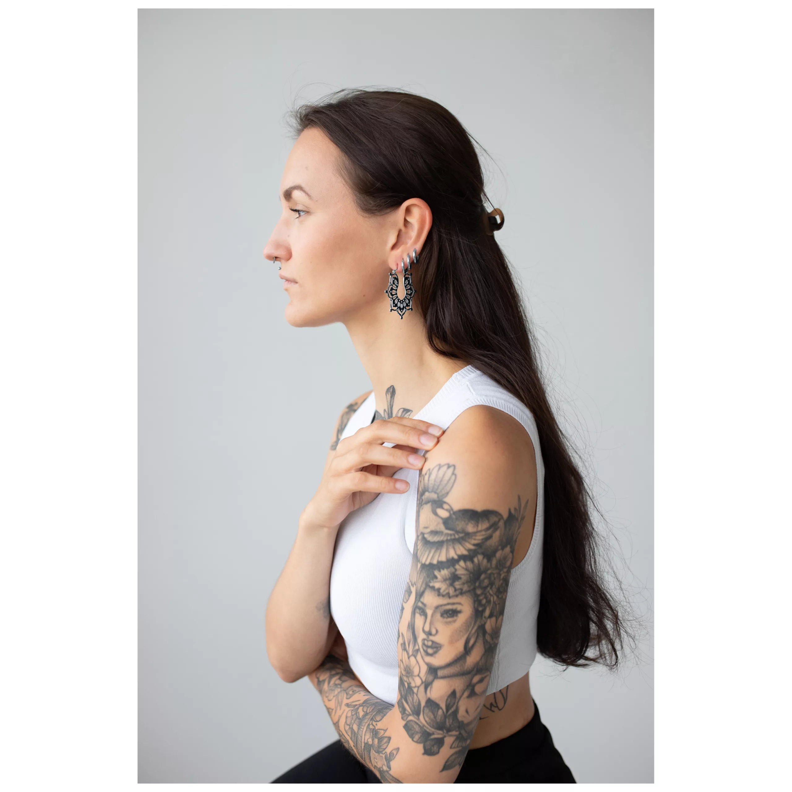Donna con orecchini Magnolia Hoops, acciaio inossidabile nero su sfondo grigio