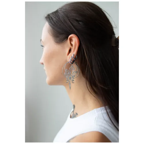 Giovane donna con capelli lunghi indossa grandi orecchini Oracle Hoops neri di profilo