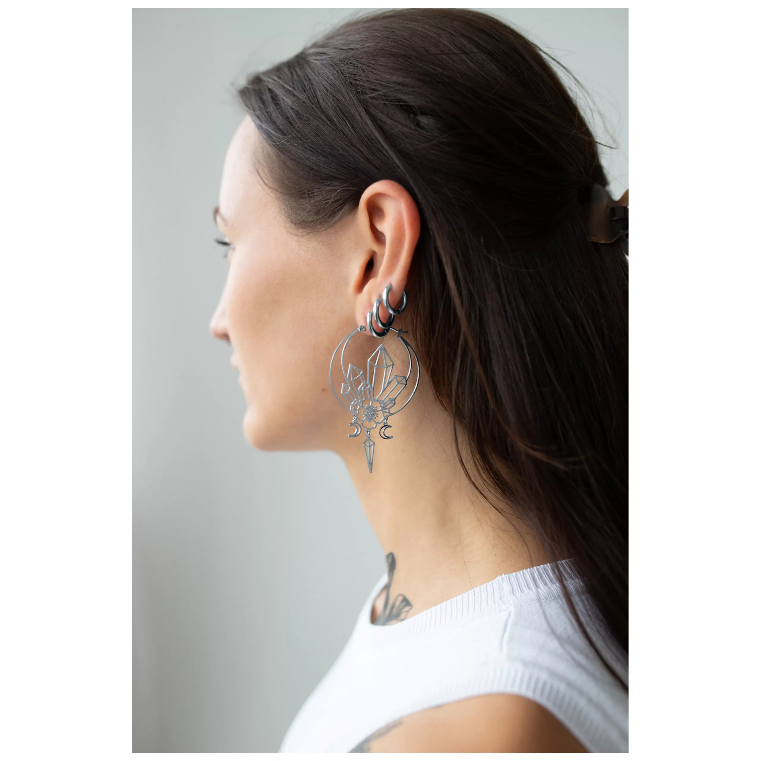 Giovane donna con capelli lunghi indossa grandi orecchini Oracle Hoops neri di profilo