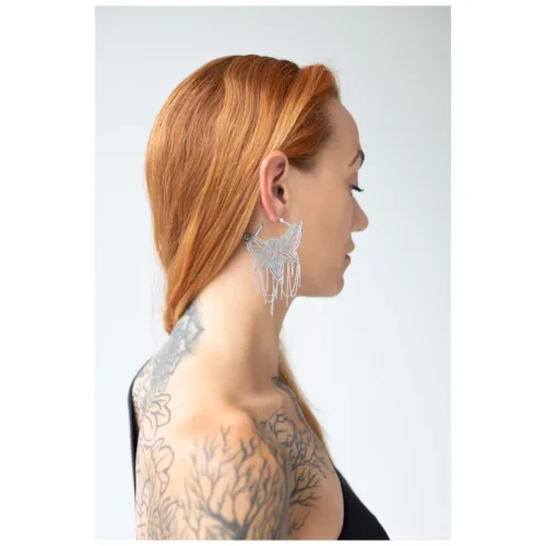 Donna con capelli rossi indossa orecchini a cerchio Moth Chain argento su sfondo bianco