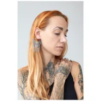 Donna con capelli lunghi indossa orecchini a cerchio Moth Chain in argento su sfondo grigio