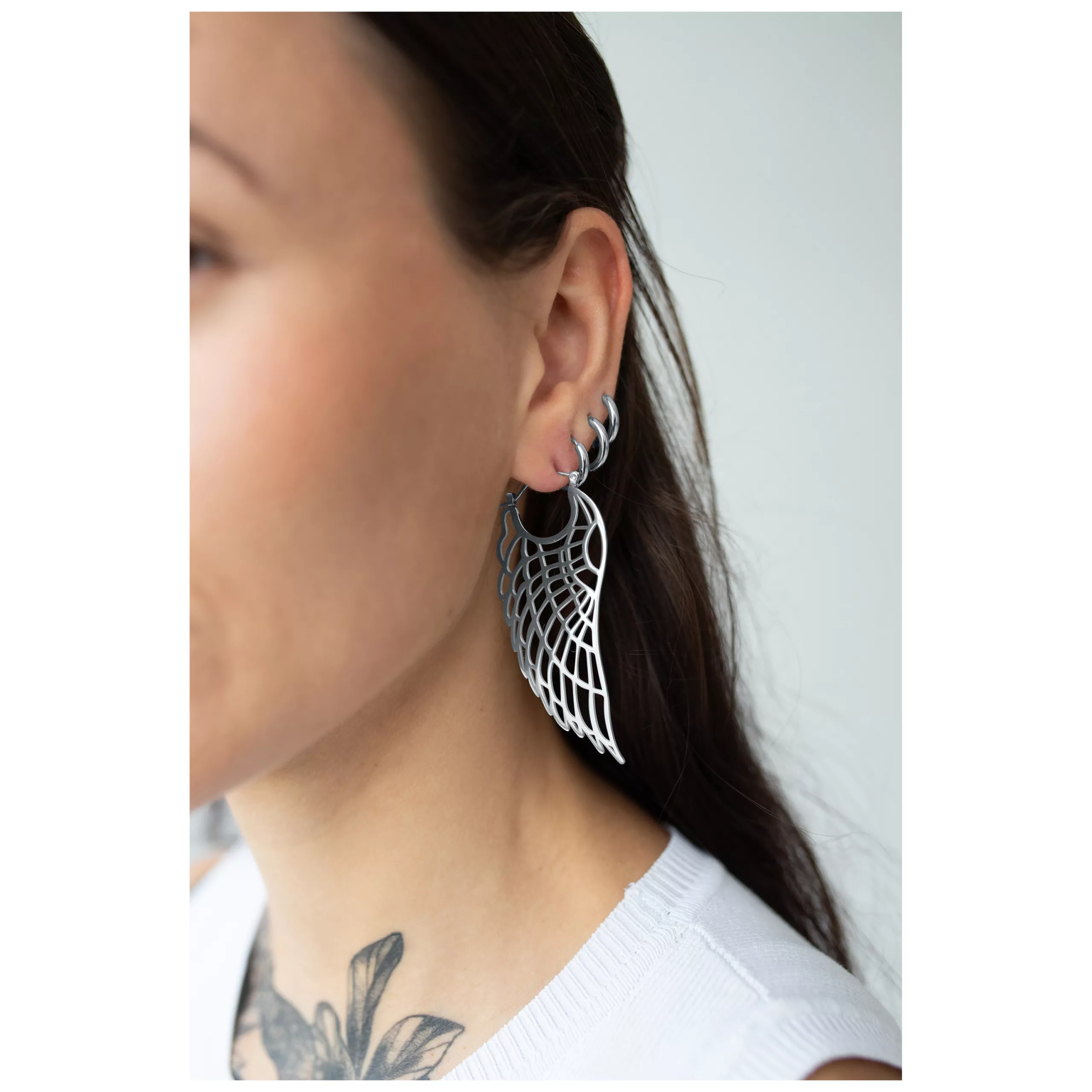 Orecchini Wing Hoops in argento in acciaio chirurgico indossati su un orecchio, lucidati a specchio e resistenti all'acqua