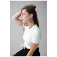 Donna con orecchini Lotus Hoops in acciaio inossidabile nero e argento su sfondo grigio