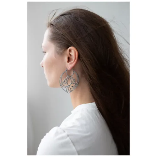 Orecchini Lotus in argento su donna con capelli lunghi e maglietta bianca