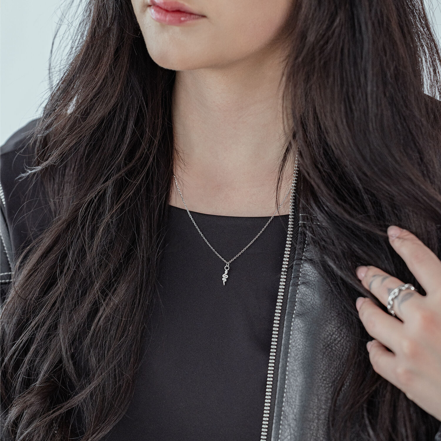 Donna con lunghi capelli scuri indossa una collana Little Snake in argento e una giacca di pelle nera