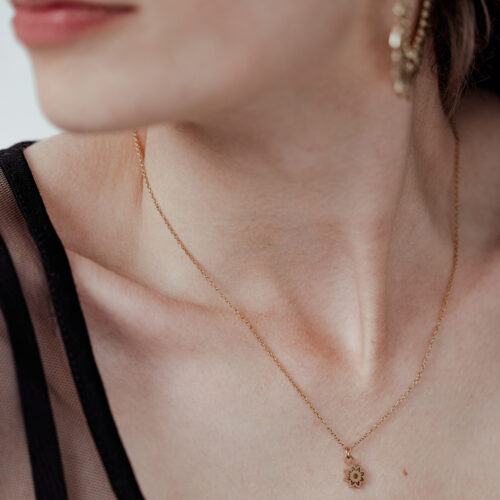 Donna con collana Little Sunflower dorata, delicata ed elegante, su sfondo chiaro