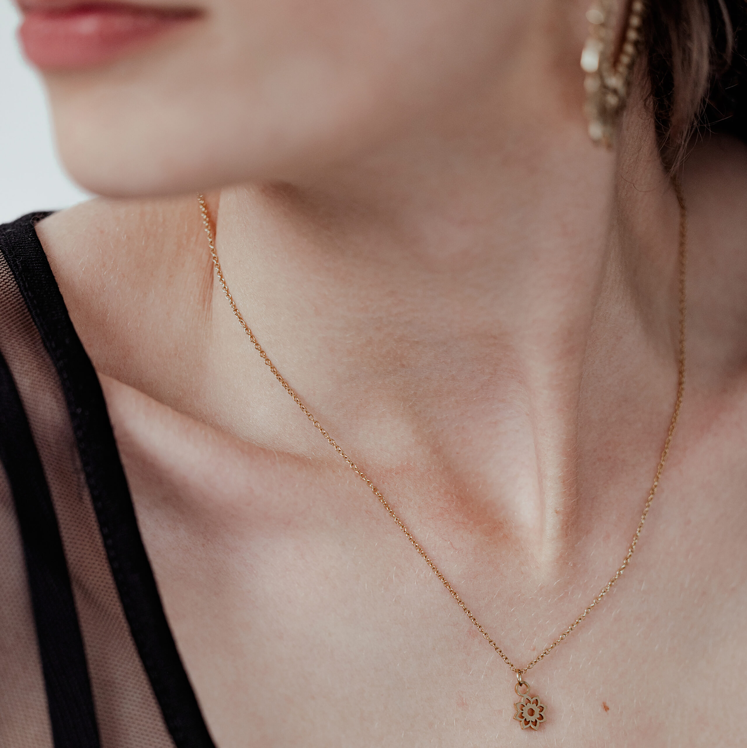 Donna con collana Little Sunflower dorata, delicata ed elegante, su sfondo chiaro