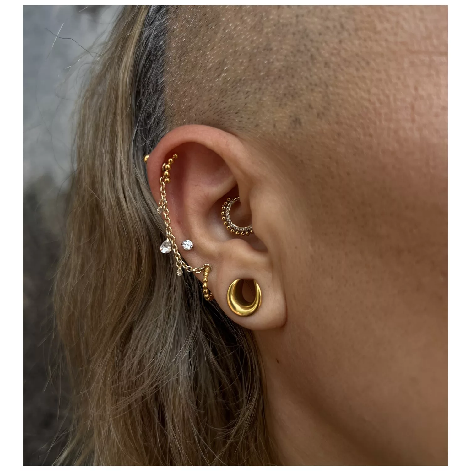 Piercing all'orecchio con Clicker in oro 14K e cristalli chiari, fotografato di lato
