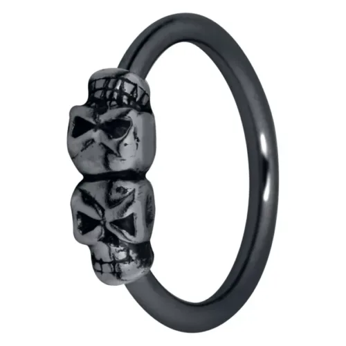 Anello nero con due piccoli teschi, in acciaio chirurgico, su sfondo bianco