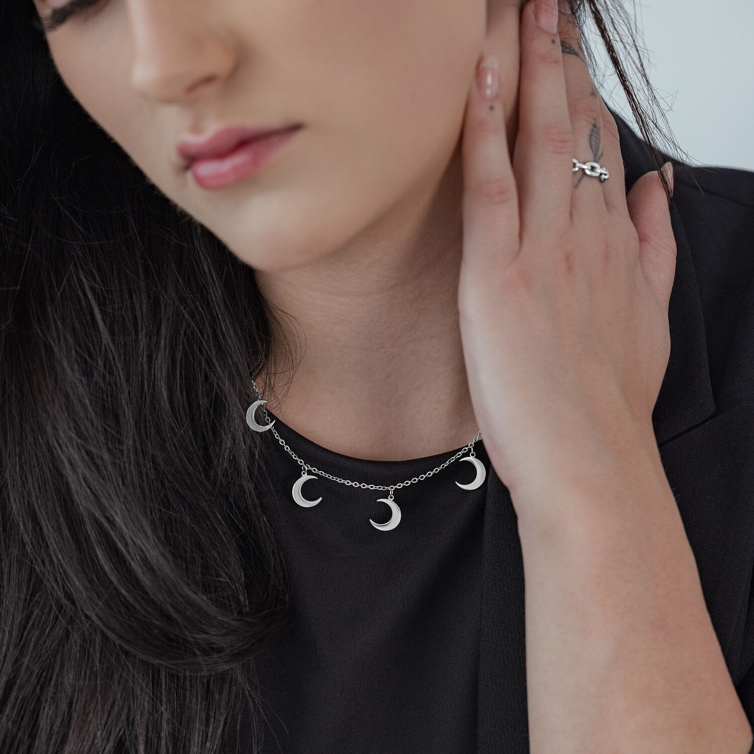 Donna indossa collana Little Moon d'argento con diversi ciondoli a forma di luna su top nero