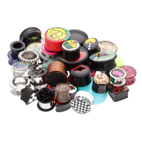 Vari piercing colorati in acrilico, acciaio chirurgico, legno e titanio su sfondo bianco