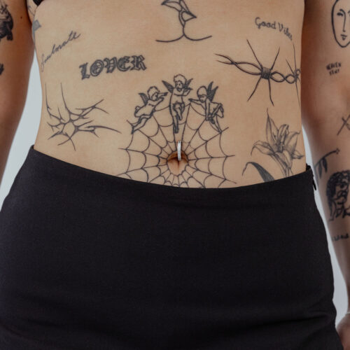 Clicker per ombelico in titanio nero con cristallo chiaro su pelle tatuata