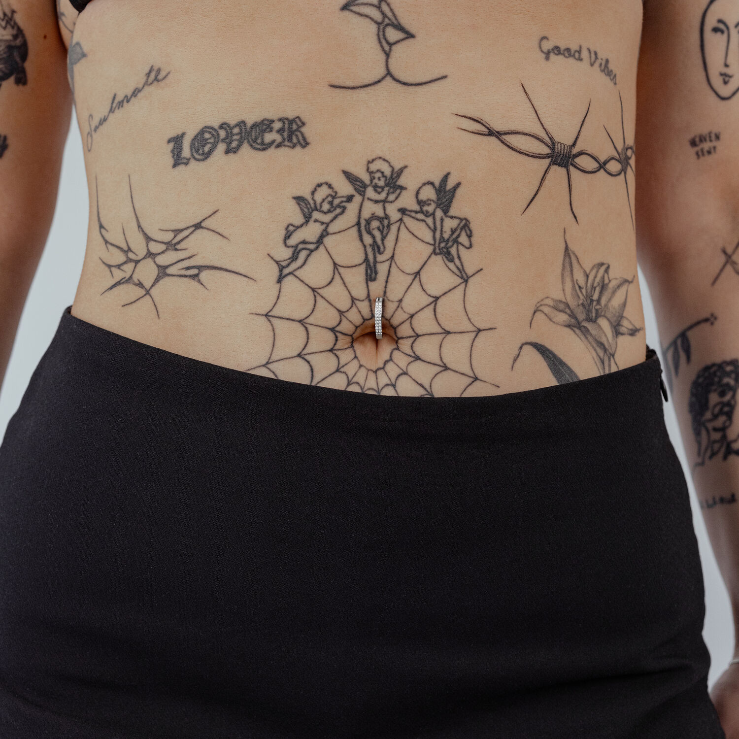 Clicker per ombelico in titanio nero con cristallo chiaro su pelle tatuata